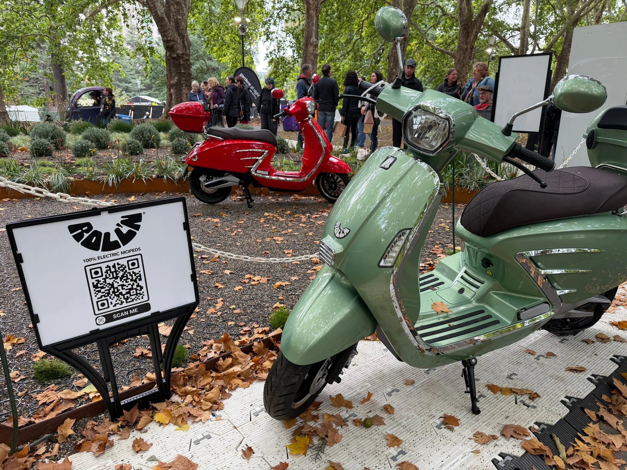 Green electric scooter motorbike moped with a QR code sign in an outdoor setting at the Melbourne international flower show with Jamie durie